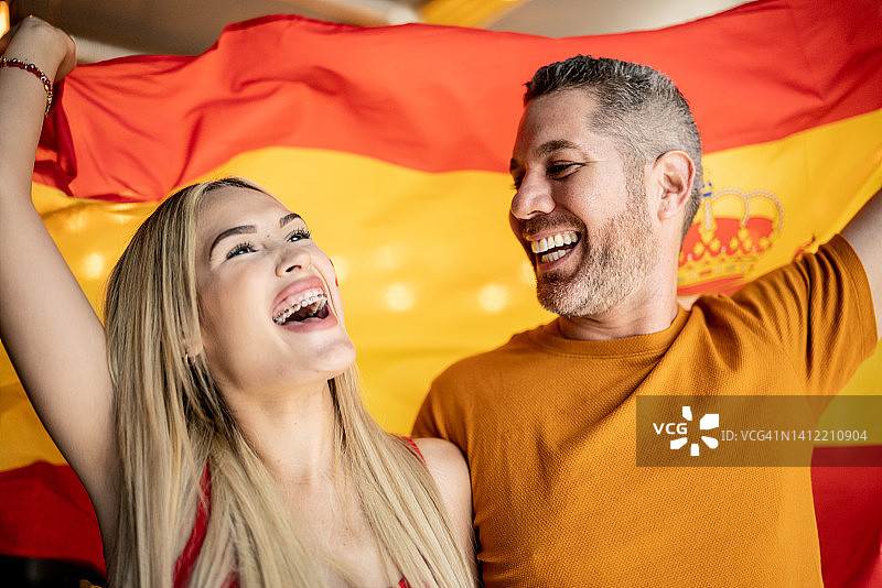朋友们在观看足球比赛，并挥舞着西班牙国旗庆祝图片素材