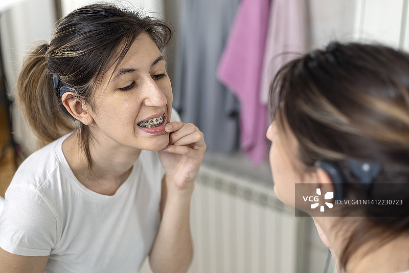戴着人工耳蜗的年轻女子照镜子图片素材