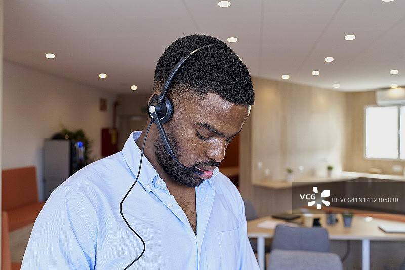 戴电话耳机的黑人男子在办公室接听电话图片素材