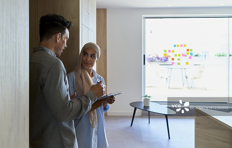 女人拿着平板和男人同事在窗前交谈图片素材