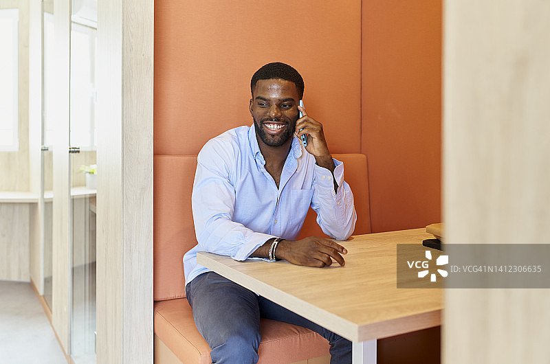 黑人男子在办公室休息时间用手机愉快地交谈图片素材