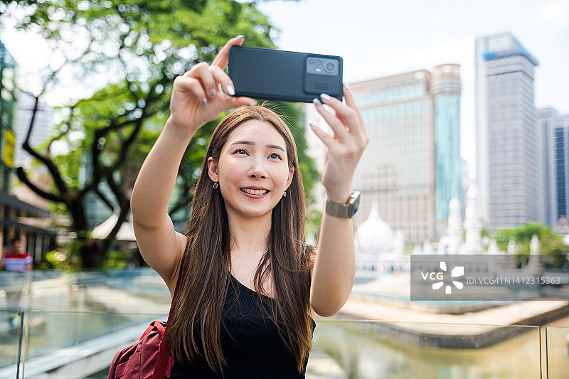 在吉隆坡占美清真寺瞭望点旅行时用智能手机自拍的亚洲女人图片素材