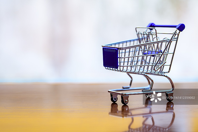 桌子上的迷你购物车或购物手推车。超市杂货手推车。购买概念图片素材