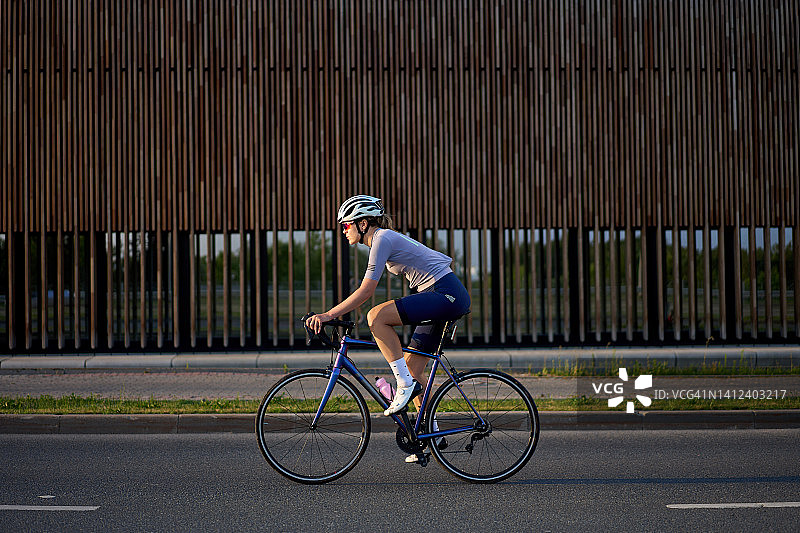 年轻女子在路上骑自行车图片素材