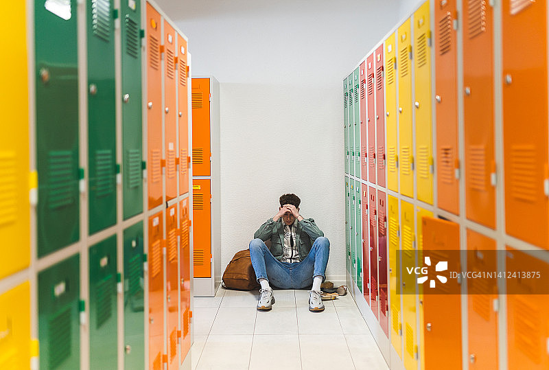 悲伤的青少年坐在更衣室的地板上图片素材