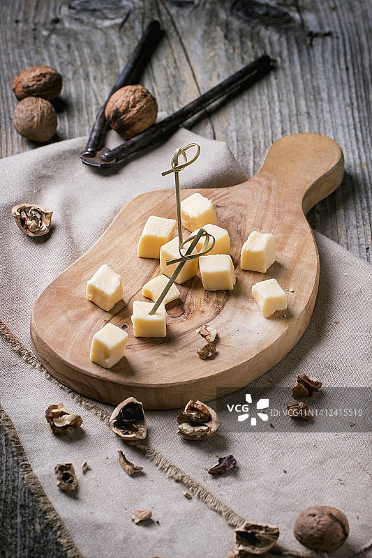 橄榄木砧板上的小块奶酪和核桃图片素材