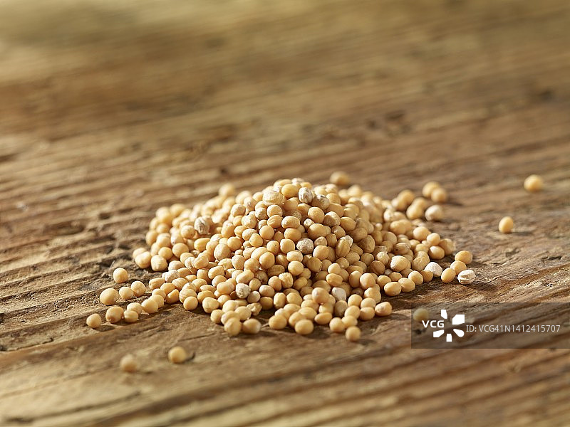 木质表面上的一堆黄色芥菜籽图片素材