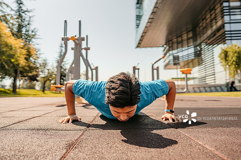 年轻男人在户外做俯卧撑图片素材