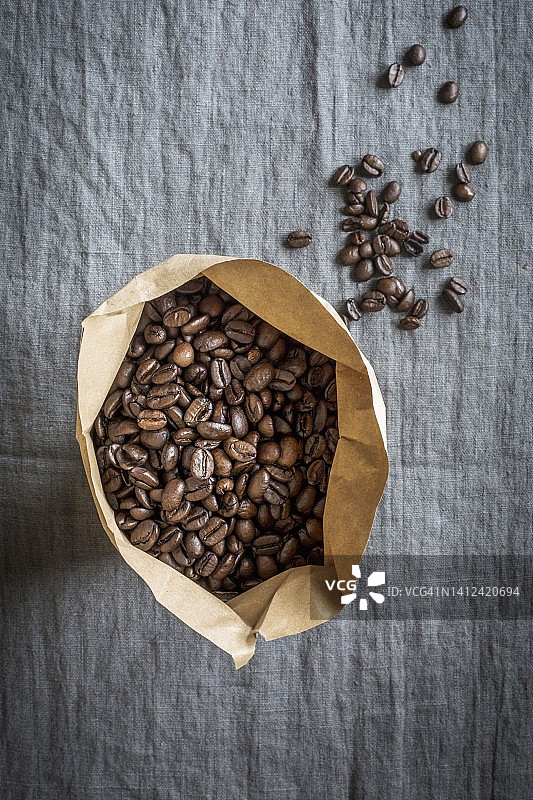 灰色亚麻布上的纸袋咖啡豆图片素材