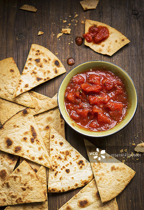 小碗番茄莎莎酱配手工玉米片，放在乡村木板上图片素材