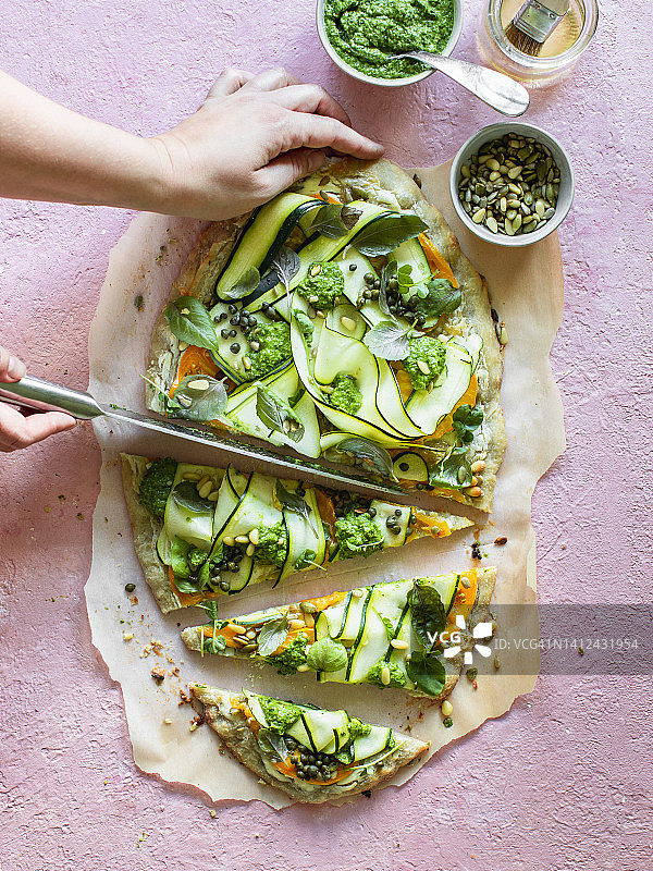 西葫芦、香草和香蒜酱披萨正在被切图片素材