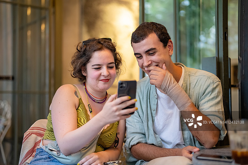 在咖啡馆里看手机屏幕的年轻朋友图片素材