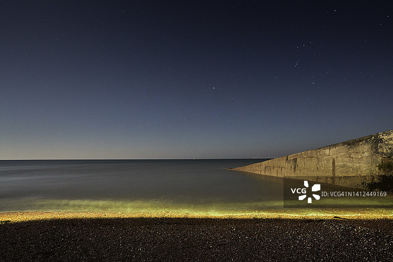 夜晚海浪中闪耀的黄色光芒图片素材