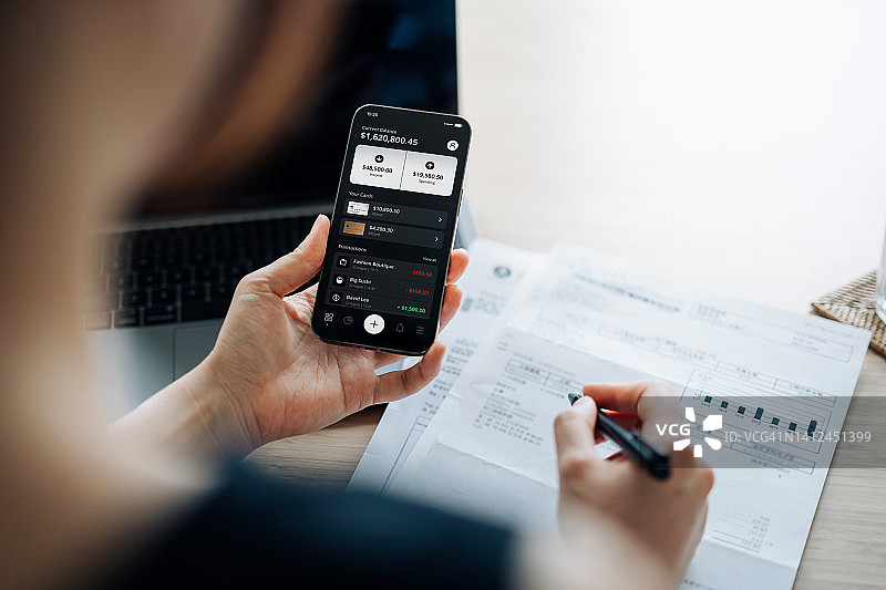亚洲女性在家用手机处理网上银行和财务图片素材