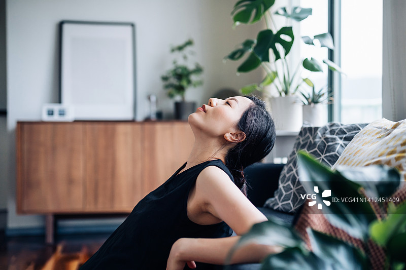 年轻亚裔女子在舒适的家中沙发上放松身心写真图片素材