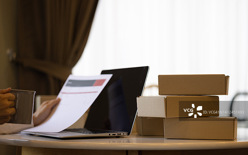 使用笔记本和包装盒的亚洲女性：电商概念图片素材