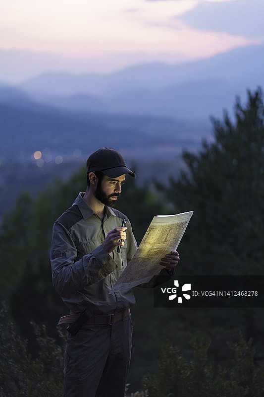 年轻护林员夜晚用手机照明查看地图图片素材