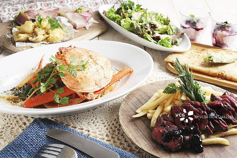 螃蟹意面、烤牛肉配薯条和混合蔬菜沙拉图片素材