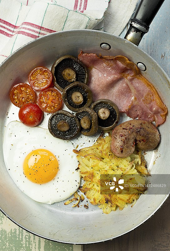 包含煎蛋、培根、薯饼、蘑菇和番茄的英式早餐图片素材