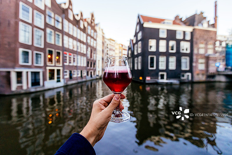 男人在荷兰阿姆斯特丹运河附近喝樱桃啤酒图片素材