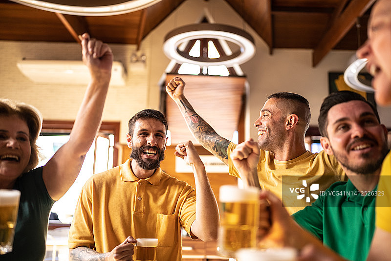 黄绿色体育迷在酒吧庆祝喝啤酒图片素材