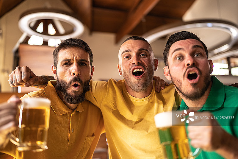 黄绿色体育迷在酒吧庆祝喝啤酒图片素材