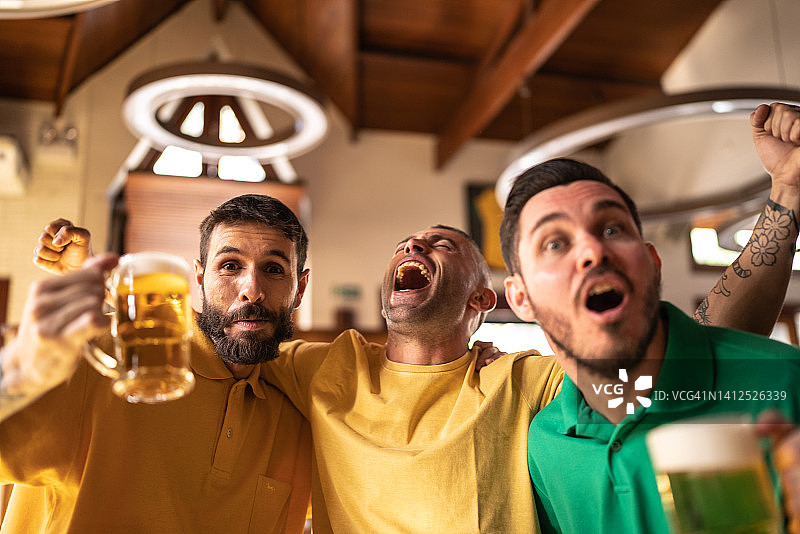黄绿色体育迷在酒吧庆祝喝啤酒图片素材