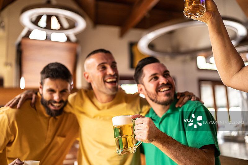 黄绿色体育迷在酒吧庆祝喝啤酒图片素材