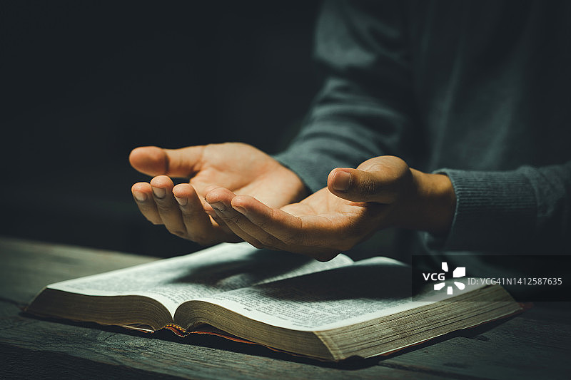 在教堂里祈祷的双手，手捧《圣经》，表达信仰、灵性和宗教概念图片素材
