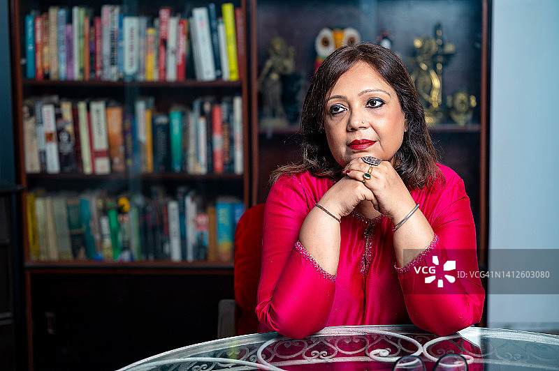 坐在家里，背景是书的沉思女人图片素材