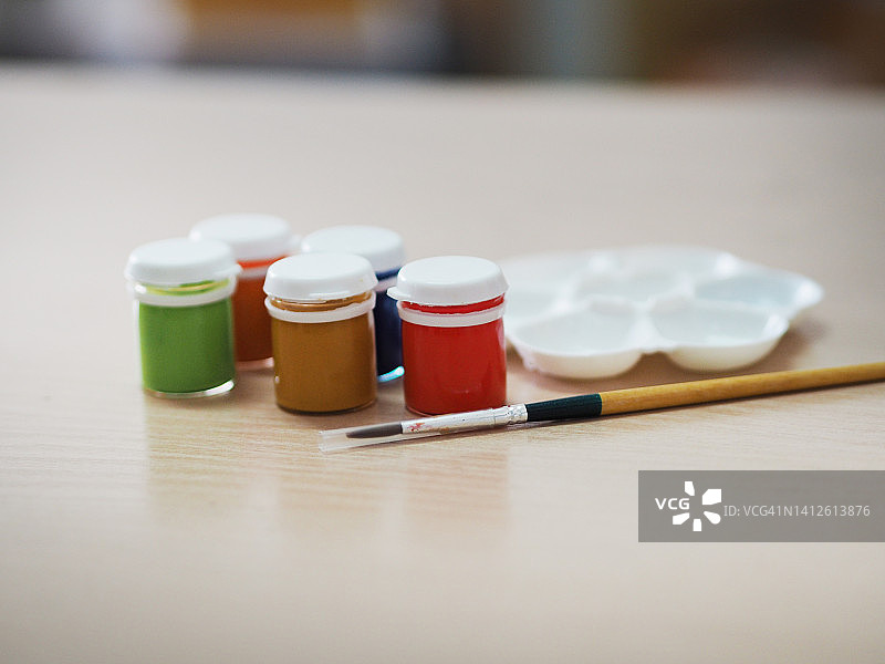 瓶装丙烯颜料和画笔（木桌上，红黄蓝绿棕橙色）图片素材