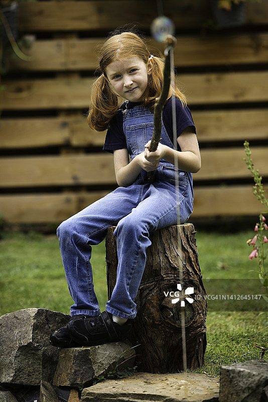 小女孩在花园池塘“钓鱼”图片素材