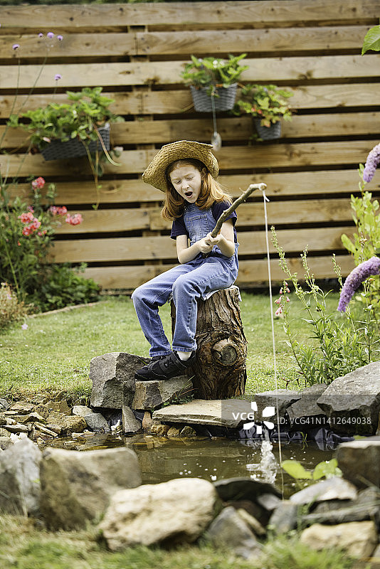 小女孩在花园池塘“钓鱼”图片素材