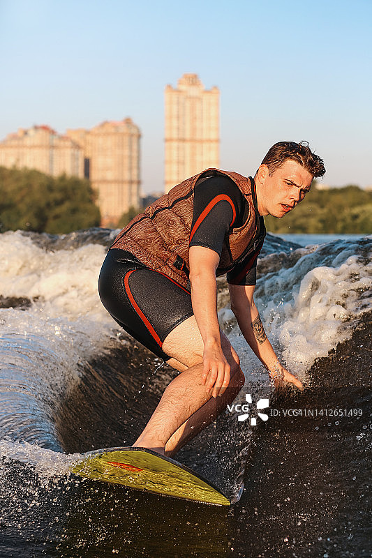 年轻英俊的业余爱好者在船后练习尾波冲浪图片素材