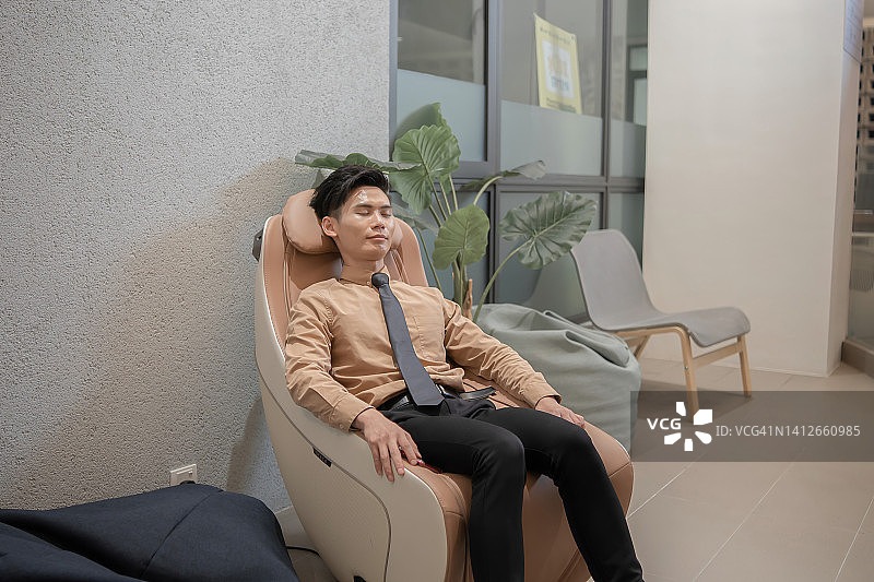 在办公室按摩椅上放松的亚洲华人商人图片素材