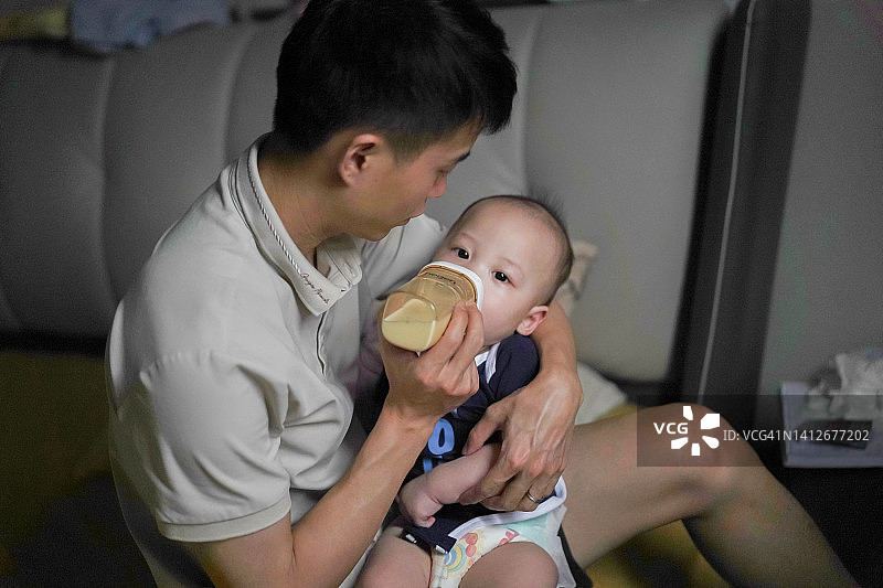 年轻的亚洲男人在喂婴儿图片素材