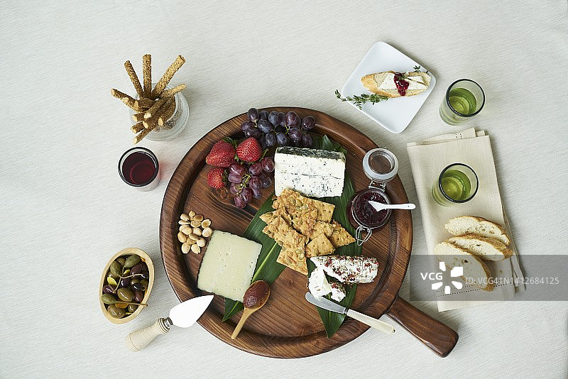 含新鲜水果、酱汁、坚果、刺山柑、面包条、饼干和白面包的奶酪板图片素材