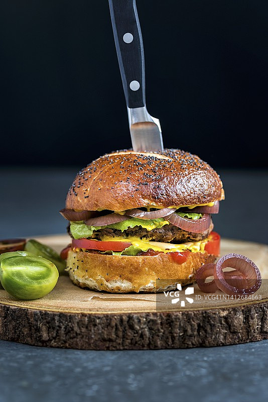 椒盐卷饼面包汉堡配芥末、番茄酱、生菜、西红柿和腌洋葱图片素材