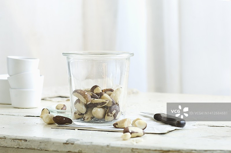 乡村厨房餐桌上的玻璃罐内和旁边的巴西坚果图片素材