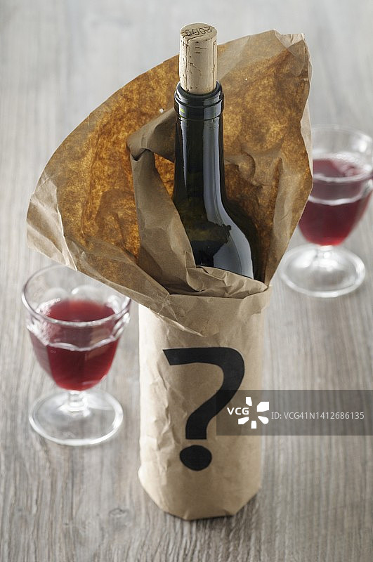 纸袋里的红酒瓶，带有一个问号图片素材