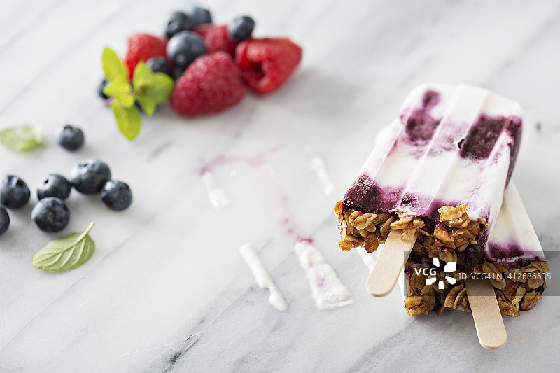 大理石台面上的酸奶、浆果和格兰诺拉麦片冰棒图片素材