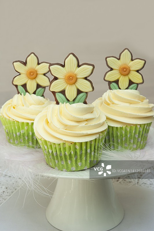 白色蛋糕架上的复活节纸杯蛋糕，饰有羽毛和巧克力图片素材