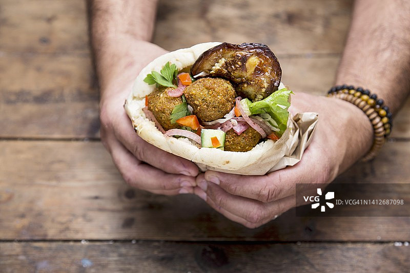 手拿一份夹着炸豆丸子的皮塔饼图片素材