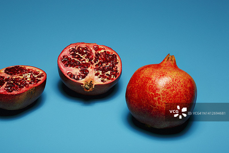 蓝色背景下的完整和切半石榴图片素材