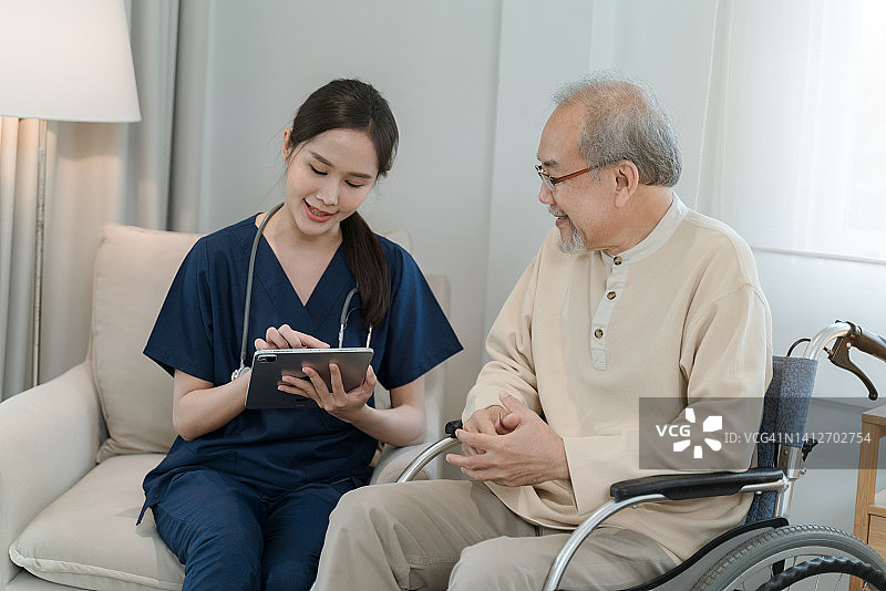 女护士在家中用平板电脑向老年男性展示医疗报告图片素材