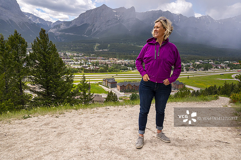 在山谷和山脉上方的小路上休息的活力女人图片素材