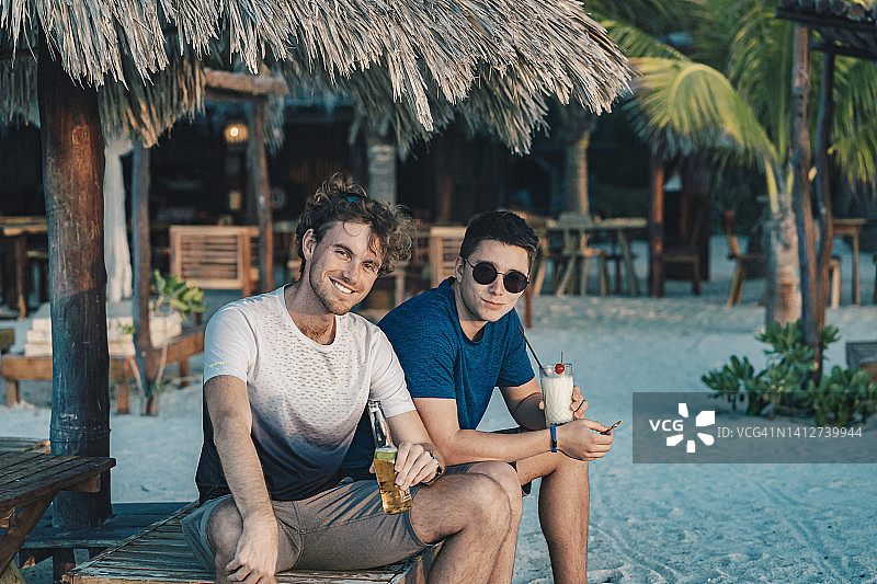 两个年轻人悠闲地在泳池边喝饮料图片素材