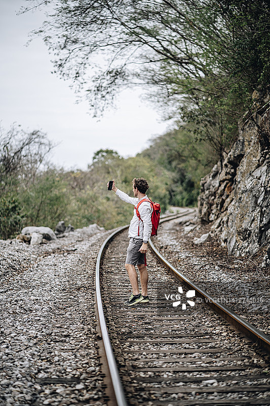 年轻男人在火车轨道上使用手机图片素材