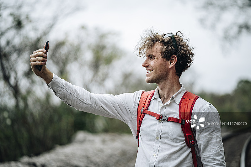 年轻男人在火车轨道上使用手机图片素材