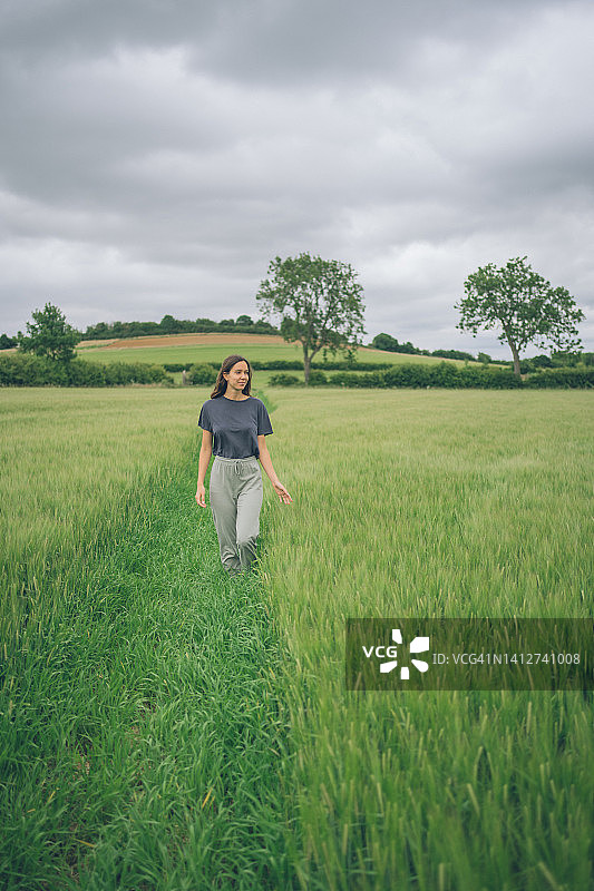 年轻女人走过绿色的田野图片素材